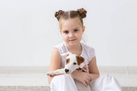 Children, pets and animal concept - Child girl play with her Jack Russell Terrier puppy indoorsの写真素材