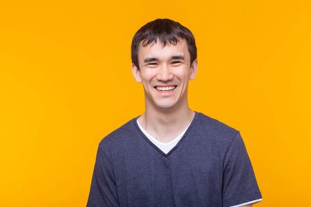 Asian handsome man wearing blue t-shirt on yellow backgroundの写真素材