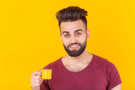 Arabic man drink coffee from small cup on yellow background - people with coffee cup easy lifestyle...