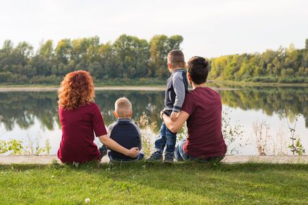 Childhood and nature concept - Family with little sons sitting on the green grassの写真素材
