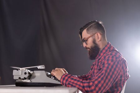 People and technology concept - Side view handsome man with beard working on typewriter over black backgroundの写真素材