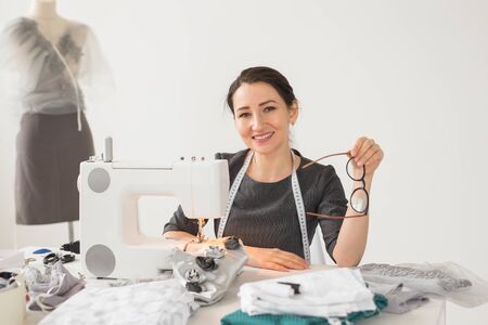 People, tailor and creative concept - Portrait of fashion designer with sewing machine over white background.の写真素材