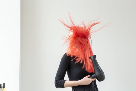 Hairdresser, style, people concept - woman is blowing dry her colored hairの写真素材