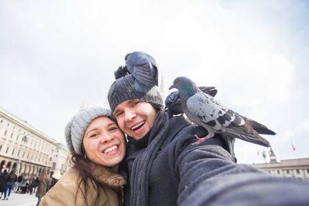 Travel, Italy and funny couple concept - Happy tourists taking a self portrait with pigeons in front of Duomo cathedral, Milanの写真素材
