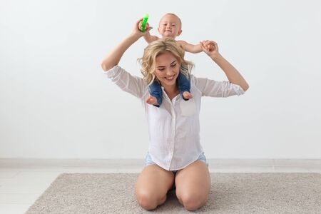family, child and parenthood concept - happy smiling young mother playing with little baby at homeの写真素材