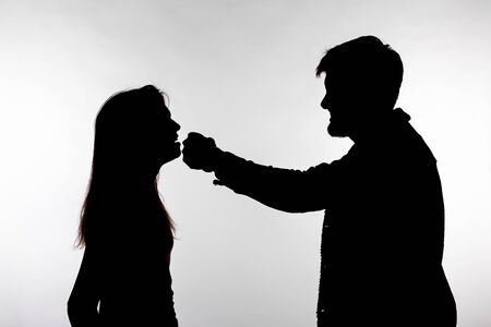 Domestic violence and abuse concept - Silhouette of man beating defenseless womanの写真素材