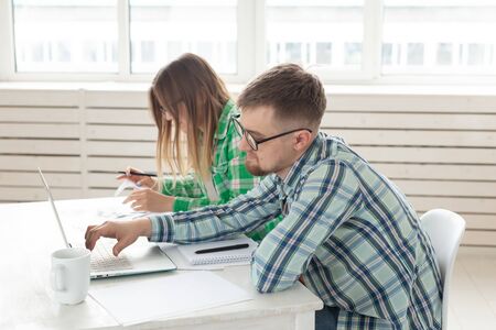 Young husband and wife are upset about numerous checks for payments and purchases for repairs while sitting at the table with a laptop. The concept of low living standards and savings.の写真素材