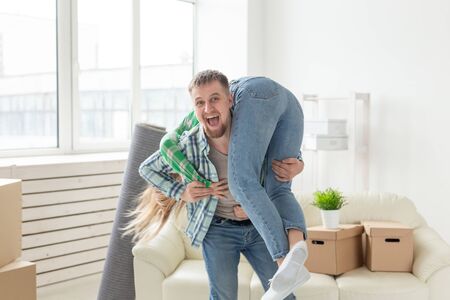 Young crazy couple in denim pants having fun rejoicing in their new apartment during the move. The concept of housewarming and credit for new housing.の写真素材