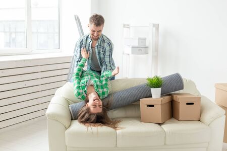 Positive crazy cheerful couple rejoices in moving their new apartment sitting in the living room with their belongings. Concept of housewarmingの写真素材