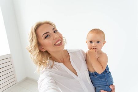 family and motherhood concept - happy young blond mother with little baby taking selfieの写真素材