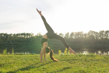 Healthy lifestyle and people concept - Flexible woman doing yoga in the summer parkの写真素材