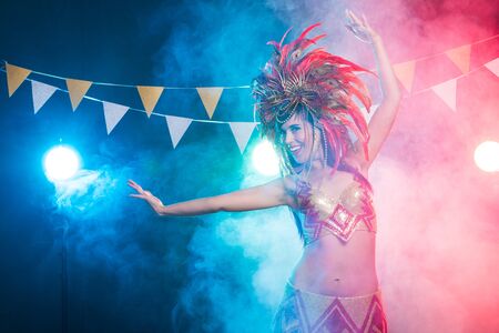 Carnival, dancer and holiday concept - Portrait of a sexy female in a colorful sumptuous carnival feather suit. Nightlife of female dancerの写真素材