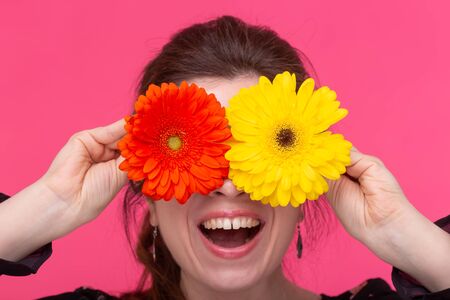 Flowers, emotions and people concept - woman closed her eyes with gerberas on pink backgroundの写真素材