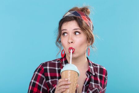 Food, diet and fun concept - pin-up woman drinking coffee or cocktail over the blue backgroundの写真素材