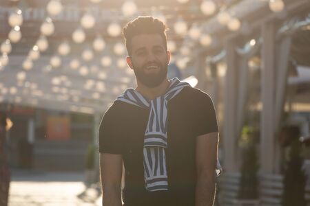 Cute stylish arab young male hipster with a mustache and a beard and wearing glasses walking on a street. Summer vacation concept.の写真素材