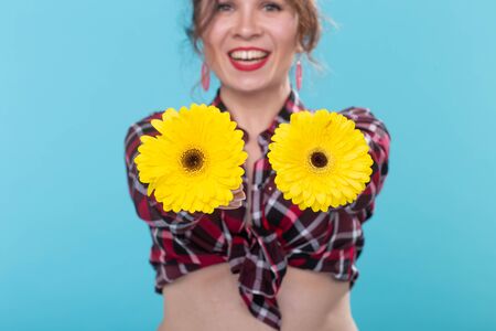 Vintage, fashion and floristic concept - woman with gerberas having fun in retro style on blue backgroundの写真素材