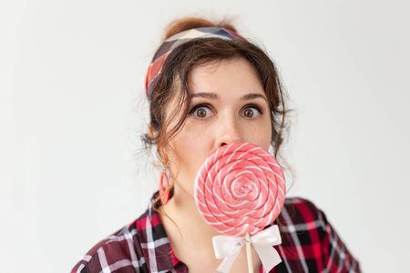 Funny beautiful young woman with bulging eyes closes her mouth with colorful lollipops posing on a...
