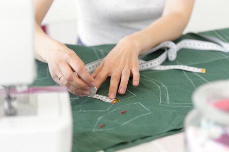 Hands of a young girl designer clothes mark for the new product with the help of chalk and measuring tape. Concept of design clothing and unique authoring products.の写真素材