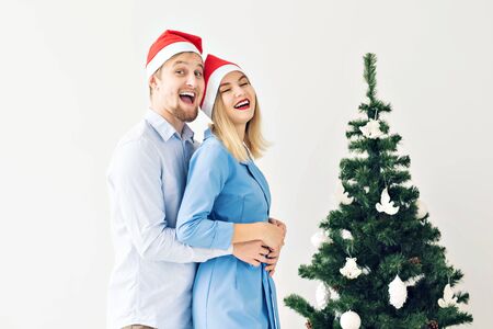 Winter holidays and family concept - Happy young couple near Christmas tree at homeの写真素材