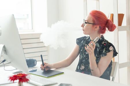 graphic designer concept - Female graphic designer working on computer while using graphic tablet at desk in the office and smoking a vapeの写真素材