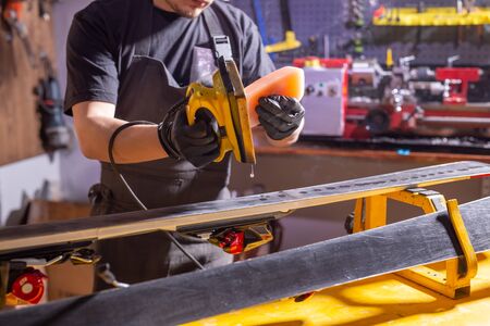 Close up of young man repairing the ski in the serviceの写真素材
