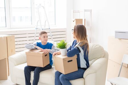Cute single mom and little boy son sort boxes with things after the move. The concept of...