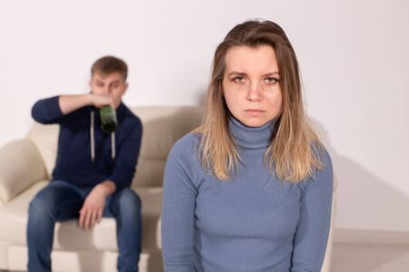 Alcoholism, abuse and domestic violence concept - sad woman with her drunk husbandの写真素材