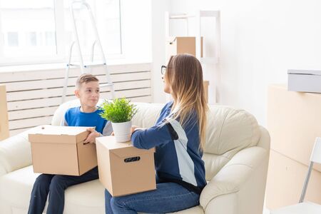 Cute single mom and little boy son sort boxes with things after the move. The concept of...