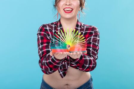 UFA, RUSSIA - APRIL 2, 2019 : pin-up woman playing with a slinky on blue backgroud