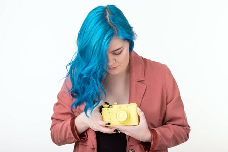 People, hobby and interests concept - Beautiful girl with blue hair hold yellow retro camera on...