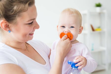 Motherhood, family and children concept - Young mother with her cute little baby at home close-up