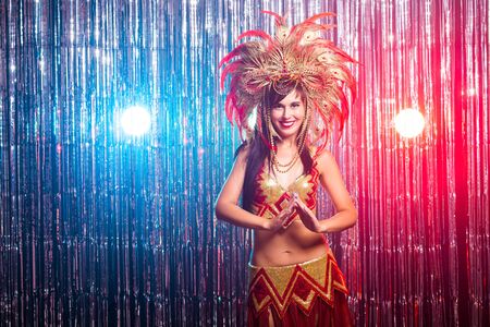 Cabaret, dancer and holidays concept - Cute young girl in bright colorful carnival costume on dark backgroundの写真素材