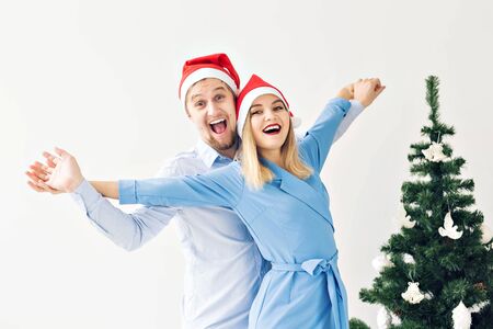 Christmas tree and holidays concept - Happy smiling family wearing santa hats celebrating at home.