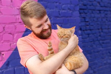 Friendship and pets concept - Handsome young man with cute cat outdoorsの写真素材