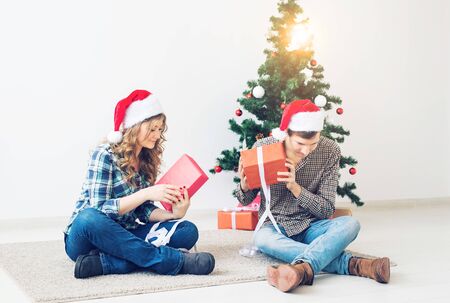 Holidays, christmas and family concept - Young happy couple opening gifts at home.の写真素材