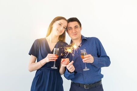 Man and woman celebrating Christmas or New Year eve party with Bengal lights and glasses of champagne on white background.の写真素材
