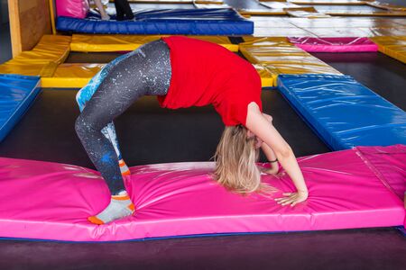 Young woman sportsman on a trampoline in fitness park and doing exercise indoors