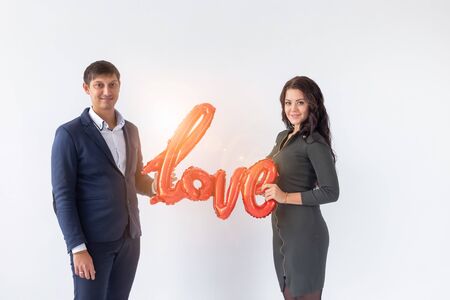 Valentines day, holiday and gift concept. Happy young caucasian couple holding love word shaped red...