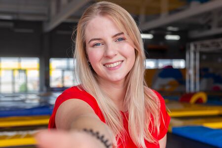 Fitness, fun, leisure and sport activity concept - Pretty young woman smiling on a trampoline indoorsの写真素材