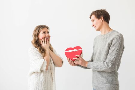 Valentines day, holiday and gift concept. Happy young couple with valentines day present isolated on a white background. Happy Man giving a gift to his girlfriend.の写真素材