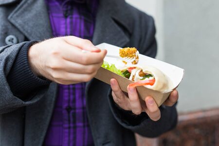 Man is holding falafel sandwich in paper bag. Healthy street food concept, oriental cuisineの写真素材