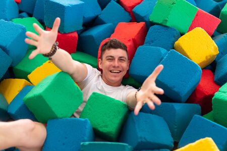 Fitness, fun, leisure and sport activity concept - Funny happy man having fun on a trampoline indoorsの写真素材