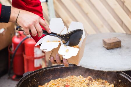 Street food - Man puts pilaf in a paper box.
