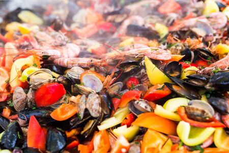 Street food concept - Gourmet seafood paella with pink marine prawns and mussels on yellow saffron...