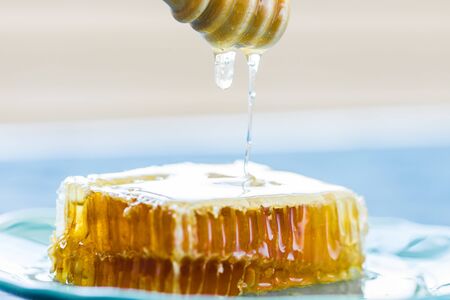 Honey with wooden honey dipper and honeycombs, close-upの写真素材