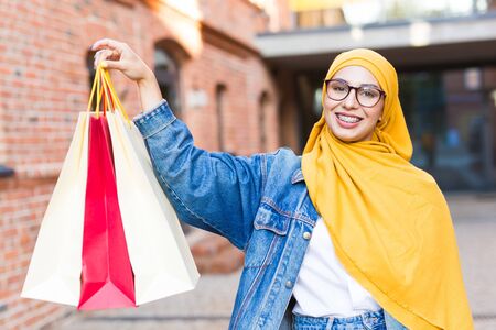 Sale and buying concept - Happy arab muslim girl with shopping bags after mallの写真素材