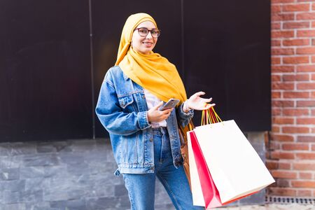 Sale and buying concept - Happy arab muslim girl with shopping bags after mallの写真素材