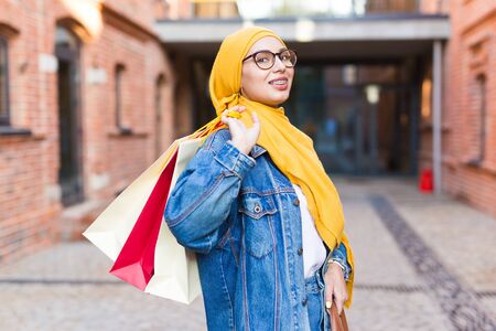 Sale and buying concept - Happy arab muslim girl with shopping bags after mallの写真素材