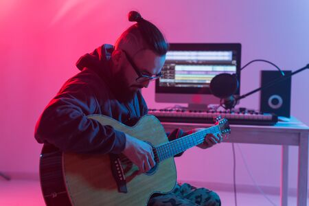 Create music and a recording studio concept - Bearded man guitarist recording electric guitar track in home studio.の写真素材