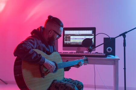 Create music and a recording studio concept - Bearded man guitarist recording electric guitar track in home studio.の写真素材